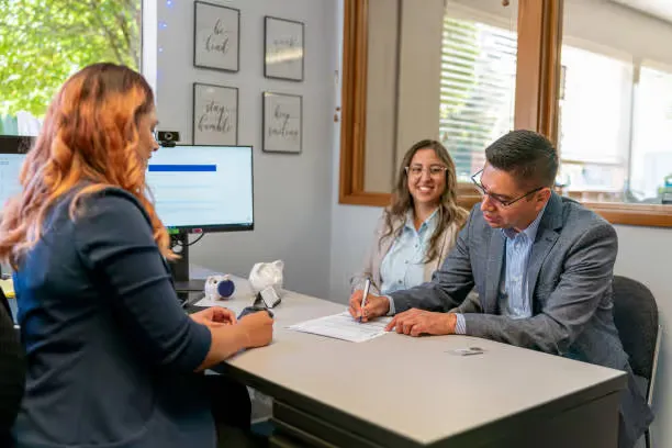 A property manager or realtor and two clients signing papers.
